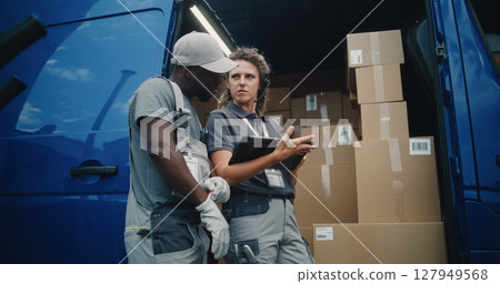 Worker and Female Inventory Specialist Talking, Using Tablet Computer, Standing near Delivery Truck Worker and Female Inventory Specialist Talking, Using Tablet Computer, Standing near Delivery Truck 127949568