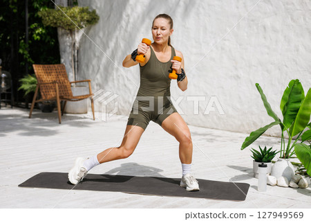 Modern home training woman exercising with dumbbells functional fitness active healthy lifestyle motivation. 127949569
