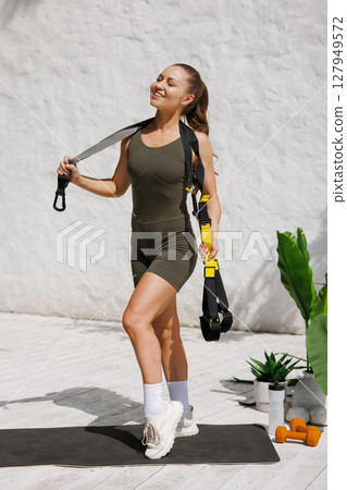 Happy fit woman with suspension straps outdoors promoting healthy lifestyle fitness and functional bodyweight exercise 127949572