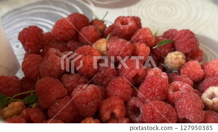 Ripe red raspberries placed in a white bowl, showcasing their natural texture, vibrant color, and freshness from the farm. Ripe red raspberries placed in a white bowl, showcasing their natural texture, vibrant color, and freshness from the farm. 127950385