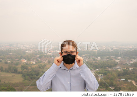 Asian businesswoman wearing N95 mask for protect Bad air pollution (PM2.5). PM2.5 levels meaning the air quality posed a health hazard. 127951689