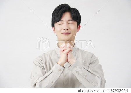 Praying man in his 20s on a white background 127952094