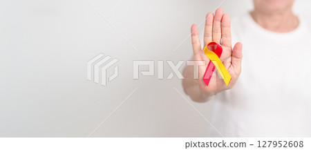 World hepatitis day awareness month, 28 July. elderly woman with Red and Yellow ribbon. Liver cancer, Jaundice, Cirrhosis, Failure, Enlarged, Hepatic Encephalopathy and Health concept 127952608