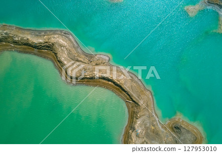 The effects of pollution on a natural habitat, featuring damaged terrain and pools of toxic water surrounded by lush hills. 127953010