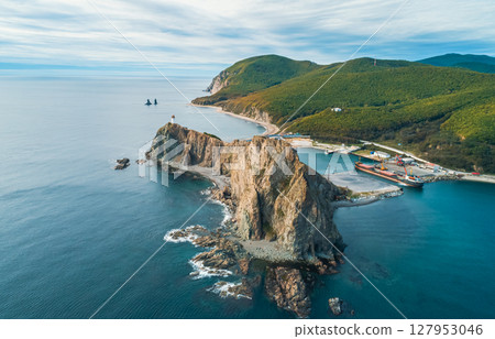 Coastal landscape featuring a harbor and rocky cliffs at sunrise with a serene atmosphere and clear waters Coastal landscape featuring a harbor and rocky cliffs at sunrise with a serene atmosphere and clear waters 127953046