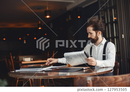Man drinks whiskey. Businessman reads documents. Director in a shirt and suspenders. Man drinks whiskey. Businessman reads documents. Director in a shirt and suspenders. 127953505