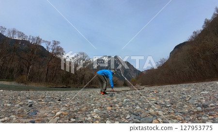 A male tourist picks up stones along the banks of the Azusa River in Kamikochi, a popular tourist spot in spring A male tourist picks up stones along the banks of the Azusa River in Kamikochi, a popular tourist spot in spring 127953775