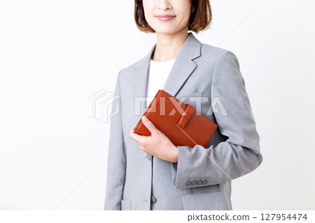 A middle-aged woman in a suit holding a notebook 127954474