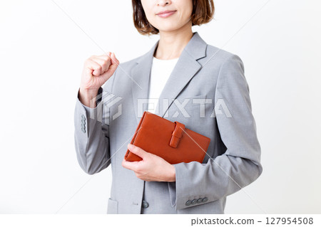 A middle-aged woman in a suit posing with a notebook 127954508