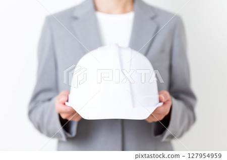 A middle-aged woman in a suit holding a helmet 127954959
