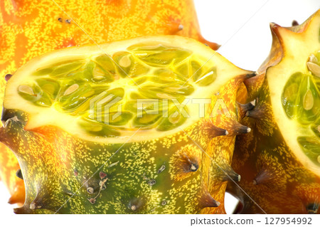 A close-up shot of horned melon highlighting its vibrant green interior and textured orange exterior A close-up shot of horned melon highlighting its vibrant green interior and textured orange exterior 127954992