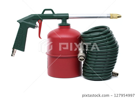 A close-up shot of an industrial air gun with a green hose and air tank on white background. 127954997