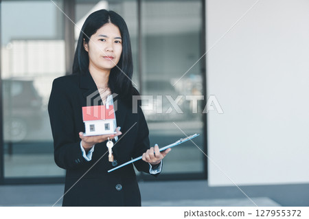Woman hand hold key buy home model business concept involves sell financial management investment bank loan ownership income economy finance investments purchasing apartment blur background estate 127955372