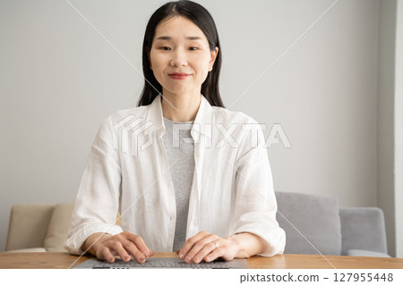A woman who operates a computer with a smile 127955448