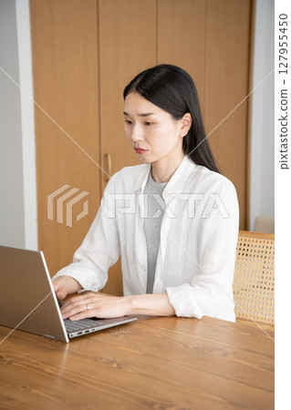 Woman operating a personal computer Woman operating a personal computer 127955450