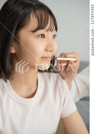 Girl getting her mother's makeup done 127955493