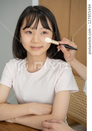Girl getting her mother's makeup done 127955494