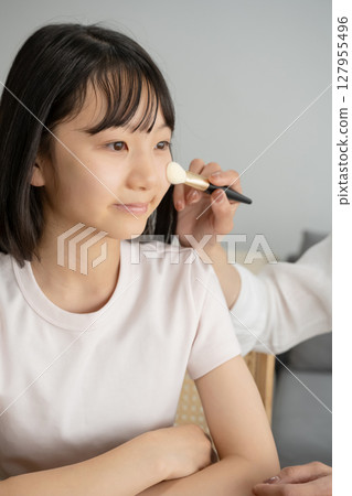 Girl getting her mother's makeup done Girl getting her mother's makeup done 127955496