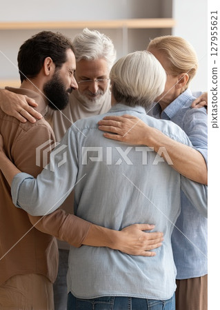 Participants uplift each other with encouraging and loving hugs. Group therapy and support: middle aged men and women hug, supporting each other during psychological practice. 127955621