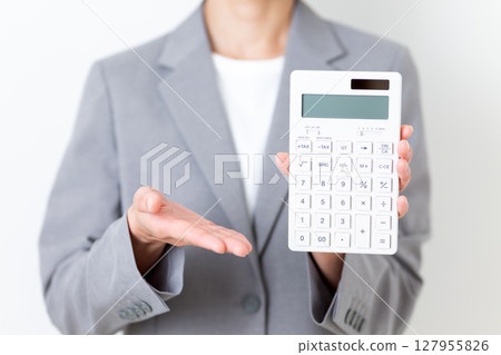 A middle-aged woman in a suit holding a white calculator A middle-aged woman in a suit holding a white calculator 127955826