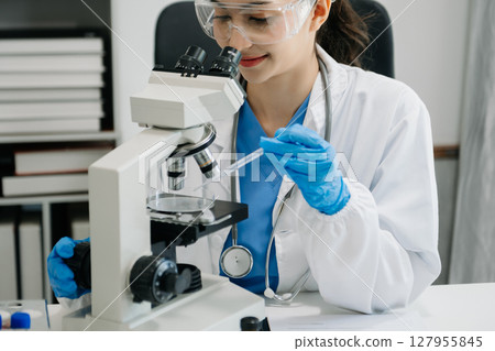 female scientist working with micro pipettes analyzing biochemical samples, advanced science chemical laboratory for medicine. 127955845