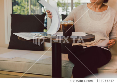 Select focus on Iced black coffee with woman reading documents in cafe. Select focus on Iced black coffee with woman reading documents in cafe. 127955852