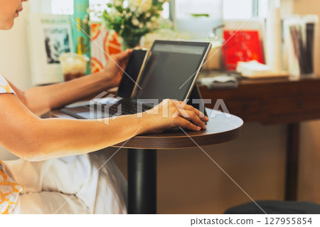 Woman hand holding computer mouse working on laptopin cafe. Woman hand holding computer mouse working on laptopin cafe. 127955854