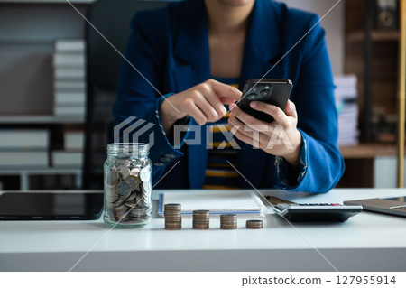 saving money with hand putting coins in jug glass and calculator to calculate budget concept finance and accounting 127955914