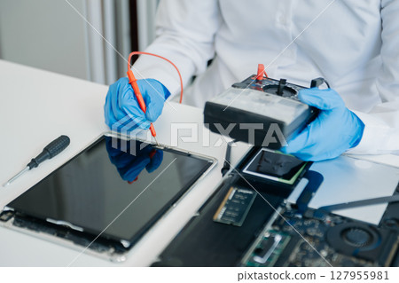 Electronics technician, electronic engineering electronic repair,electronics measuring and testing, repair and maintenance concepts.uses a voltage meter to check and upgrade in shop 127955981