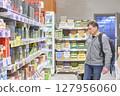 Man Carefully Considers Grocery Shopping Options Today 127956060
