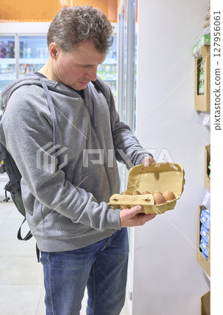 Person Carefully Examines Fresh Eggs At Grocery Store Person Carefully Examines Fresh Eggs At Grocery Store 127956061