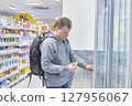 Man Carefully Selects Beverage From Cooler Display 127956067