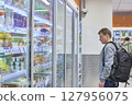 Man Browses Refrigerated Goods At Grocery Store 127956075