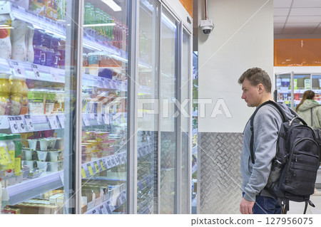 Man Browses Refrigerated Goods At Grocery Store Man Browses Refrigerated Goods At Grocery Store 127956075