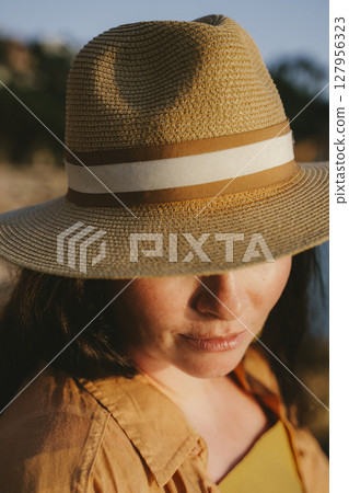 Woman Wearing Straw Hat in Sunlight 127956323