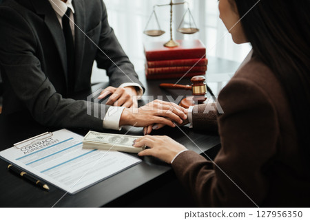 Judge gavel with scales of justice, Business and lawyer or counselor consulting and discussing contract papers with laptop and tablet at law firm 127956350