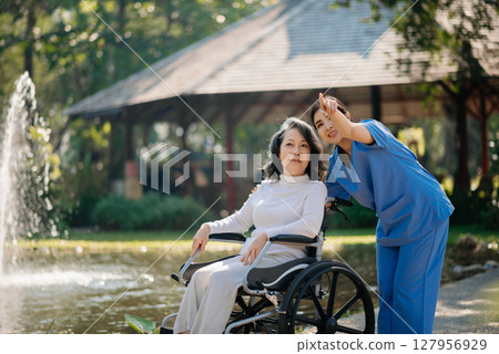 Asian young caregiver nurse support senior older male walking outdoors. Specialis doctor help and take care of elderly mature. 127956929