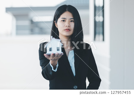 Woman hand hold key buy home model business concept involves sell financial management investment bank loan ownership income economy finance investments purchasing apartment blur background estate 127957455