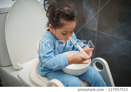 toddler girl washing nasal with syringe and saline by herself. cleaning nose 127957553