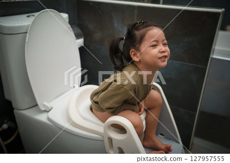 happy toddler girl is sitting on the toilet at home. potty training and learning 127957555