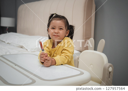 happy toddler girl holding syrup medicine with syringe 127957564