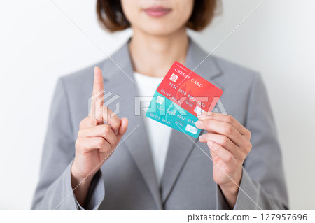 A middle-aged woman in a suit holding a credit card and pointing her index finger up 127957696