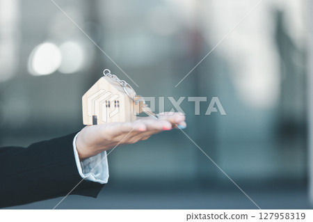Woman hand hold key buy home model business concept involves sell financial management investment bank loan ownership income economy finance investments purchasing apartment blur background estate 127958319