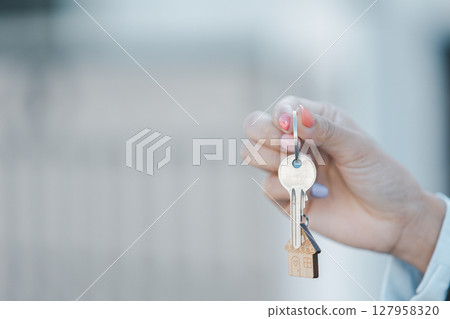 Woman hand hold key buy home model business concept involves sell financial management investment bank loan ownership income economy finance investments purchasing apartment blur background estate 127958320