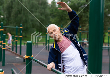 Old man warming up before training outdoors Old man warming up before training outdoors 127958436