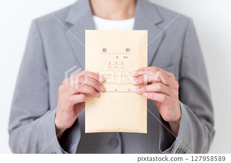 A middle-aged woman in a suit holding a pay envelope 127958589