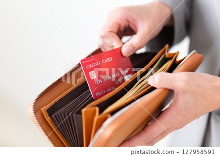 A middle-aged woman in a suit taking a credit card out of her wallet 127958591