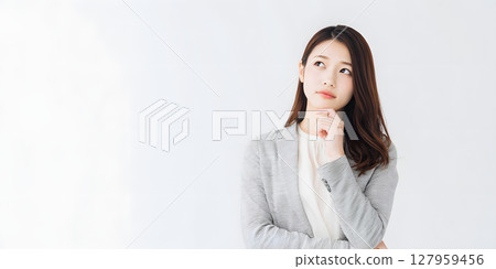 一位年輕的日本女性陷入沉思。白色背景的商業資料突顯了她的面部表情 127959456