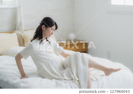 抽筋的女人坐在臥室的床上 抽筋的女人坐在臥室的床上 127960043