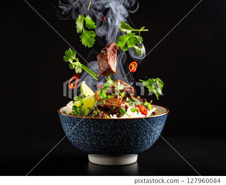 AI generated smoky thai sue rong hai grilled beef with fresh ingredients falling into ornate thai bowl juicy marinated steak spicy dipping sauce aromatic herbs 127960084